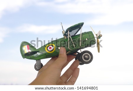 toy plane, green toy aeroplane in human hand act flying in the sky