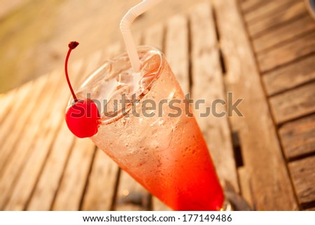cocktail, red cocktail fruit decorate with cherry on wood table by the sea