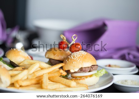 french fries, fried tomato with mini hamburger on a dish decorated