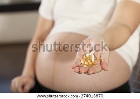pregnancy care, Asian pregnant woman shows medicines vitamin pills in her hand