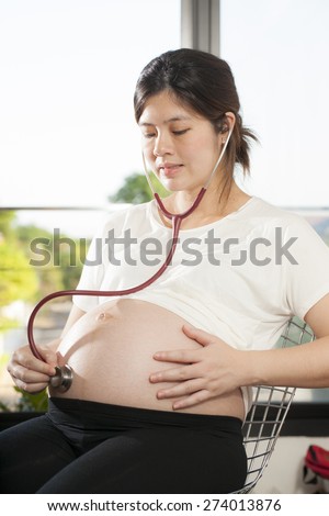 Pregnancy, an Asian doctor use stethoscope check at pregnancy belly of Asian woman