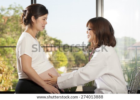 Pregnancy, an Asian doctor use stethoscope check at pregnancy belly of Asian woman
