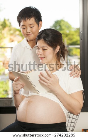 pregnancy care, Young Asian boy sharing times with his mother reading a book