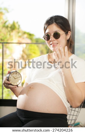pregnancy count down, An Asian woman holding clock count down for baby delivery in four weeks