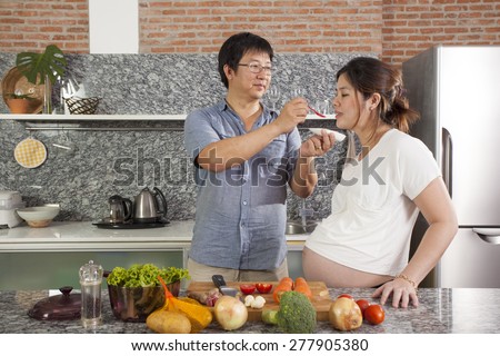 pregnant care, pregnancy Asian woman taste food in the kitchen with a brother or husband