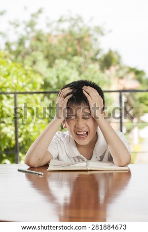 headache boy, an Asian young boy squeeze his head for homework like crazy