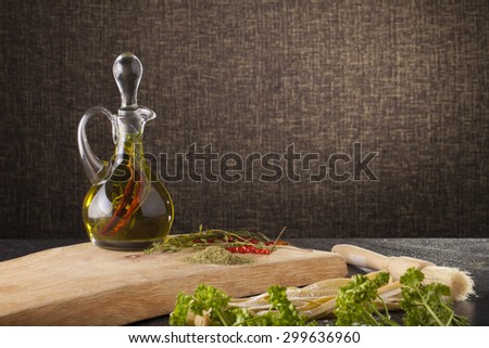 olive oil, a nice glass jar of seasoning olive oil with decorated fresh pasta and herbs on background