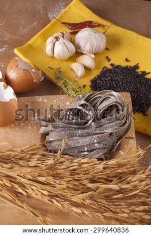 black pasta, close-up to uncook dried black pasta mix with black rice decorate rice and garlic background, Thailand