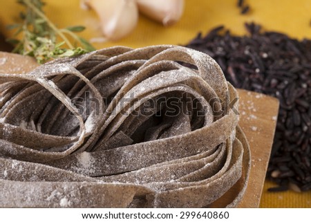 black pasta, close-up to uncook dried black pasta mix with black rice decorate rice and garlic background, Thailand
