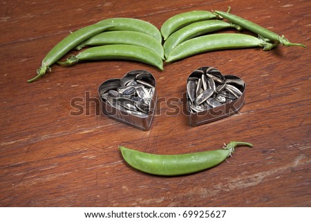 Vegetable face, Peas and sunflower seeds arrange as a smiling face with a heart shape eyes, funny.