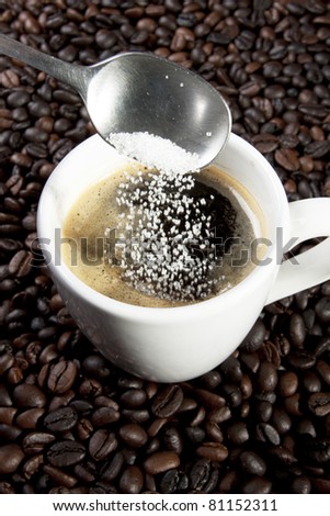pour sugar, sugar pouring with spoon in a cup of espresso coffee.