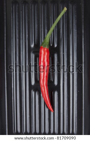 red chili, one red Thai chili on black tray.