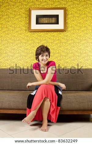 cozy corner, female model sitting on cozy sofa with yellow wallpaper.