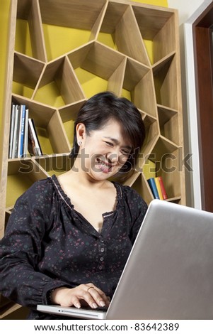 funny chat, female model laughing using laptop for chatting online.