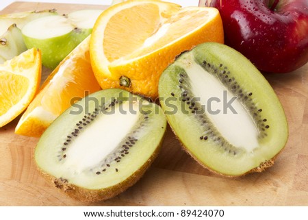 mix fruit, cut kiwi, orange, red and green apple mixed on wood plate.