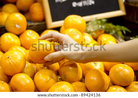 pick orange, female hand pick up Sunkist orange in market.