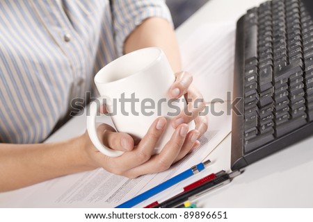 coffee time, female officer holding white coffee cup during working time at office.
