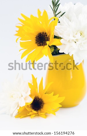 Yellow jug with yellow and white flowers on a light background