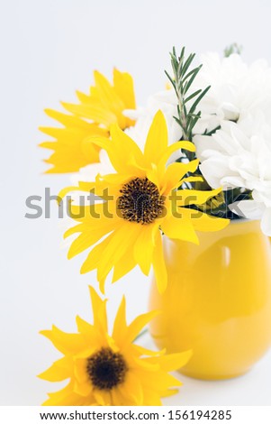 Yellow jug with yellow and white flowers on a light background