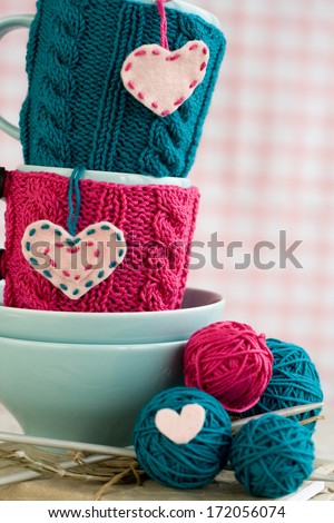 Two blue cups in blue and pink sweater with felt hearts