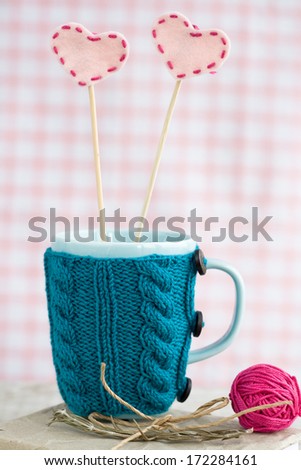 Blue cup in a blue sweater with felt hearts