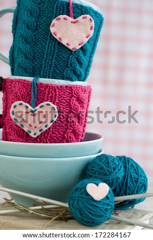 Two blue cups in blue and pink sweater with felt hearts