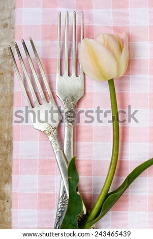 The two dessert forks are near tulip on a tablecloth