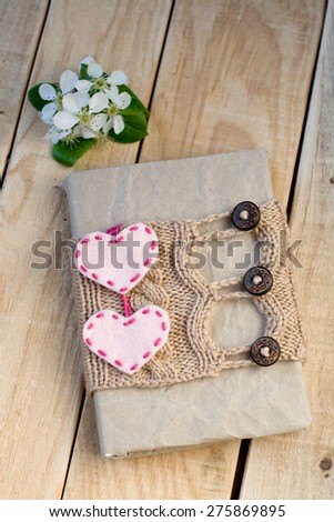 Old vintage notepad Knitted sweater in beige, hearts of felt on wooden background.