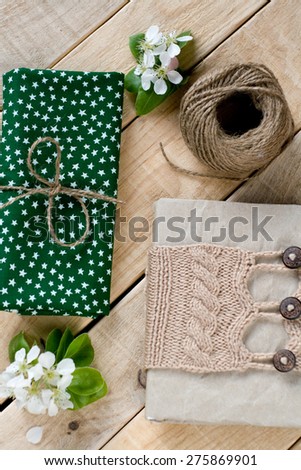 Old vintage notepad knitted in beige sweater, thick skein of yarn, cloth, flower pear lying on unpainted wooden background.
