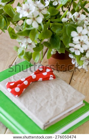 A bouquet of flowering branches of fruit trees and an old notepad on unpainted wooden background