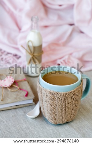 Blue cup of coffee in Knitted sweater, vintage notebook for records in a bottle with milk