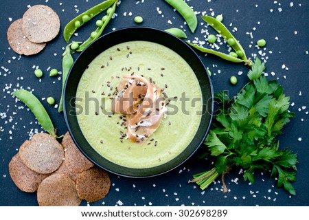 Healthy green soup with ham and peas on a black background