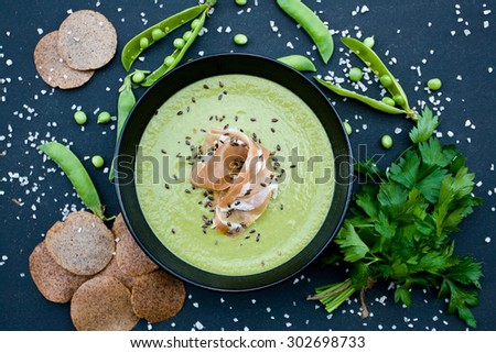Healthy green soup with ham and peas on a black background