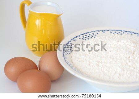 Pitcher of milk, eggs and flour on a white background