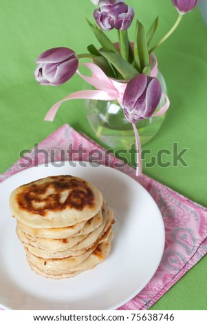 Delicious pancakes for breakfast and a vase with a bouquet of tulips