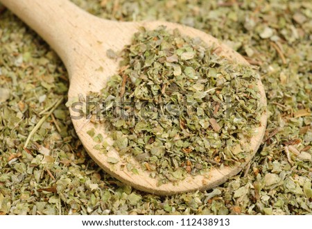 Dried marjoram spice and wood spoon as food background