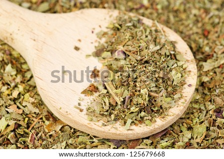Pile of ground dried Basil (Sweet Basil) as background with wooden spoon. Used as a spice in culinary herb all over the world. The plant is also used in medicine.