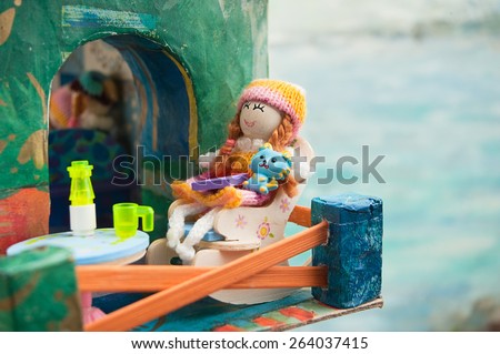 doll on the balcony of toy house, on a background of the sea