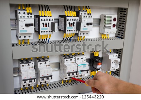 Technician working at electrical cabinet (using a screwdriver).