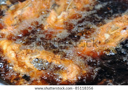 Breaded chicken deep frying in oil in a cast iron frying pan