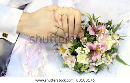 Just married couple hands with flowers bouquet.
