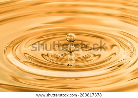 Dripping yellow gold water drop closup.