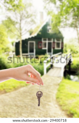 Handing over house key with a new home in the background