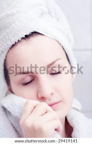 Woman in towel with hand on cheek