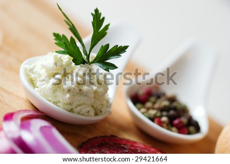 Two spoons with spices and one with cheese with parsley on top