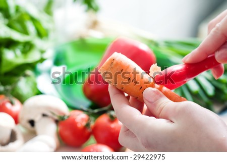 Peeling carrot on a vegetable background, in the kitchen