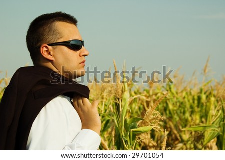 Business man in a corn field, watching the sky