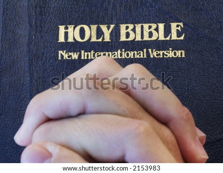hands folded on bible to pray