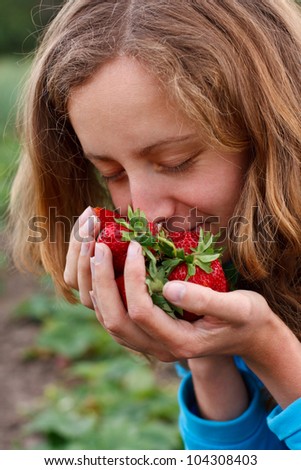 Young woman with red fresh strawberries in hands. Enjoying the aroma of ripe strawberries