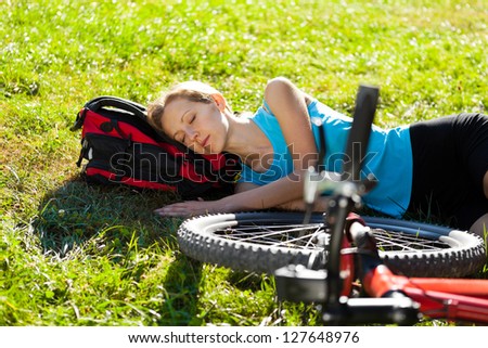 Young cyclist enjoying sleeps relax lying in the fresh grass in spring park. Outdoor